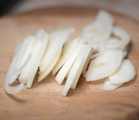 Fototapeta na wymiar Onion and onion slices on wooden cutting board.