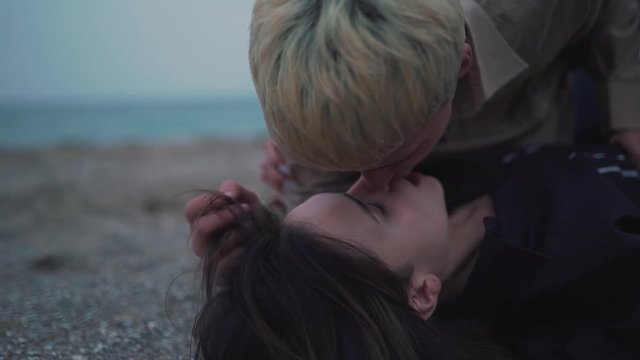 Couple lie on the sand and kissing.