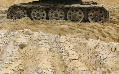 old iron caterpillar in wet sand. Rusty steel wheels and caterpillar tape of a large  bulldozer, tank, excavator, in damp sand and puddles.