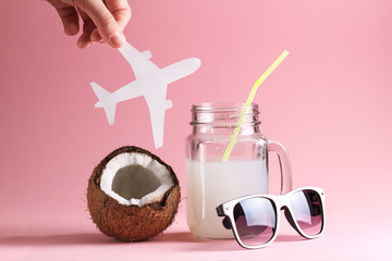 Coconut cocktail, white glasses, airplane on a pink background. Theme of vacation.
