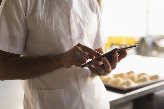 Male baker using digital tablet in bakery shop