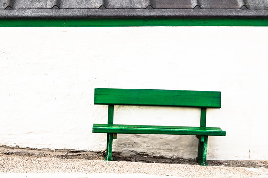 Green Bench in front of a white Wall