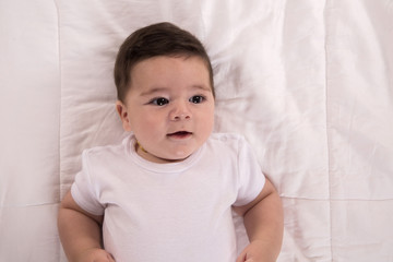 baby smiling lying in bed and looking aside