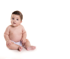 Adorable baby sitting and looking for camera over white background