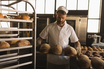 Male baker holding a tray of baked breads