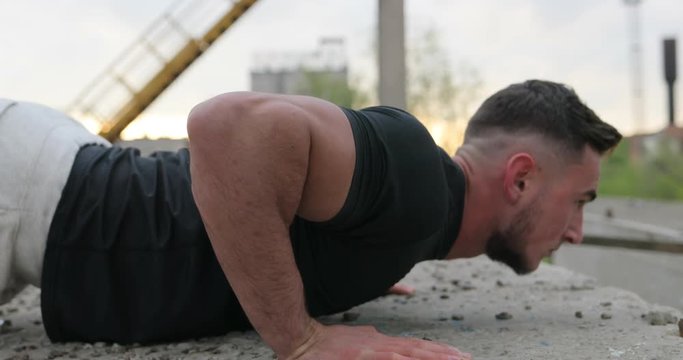 Side view of young handsome man in sportswear doing push-up outdoor. Strength and motivation. Portrait of a fitness man doing push ups
