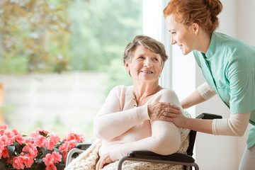 Young nurse helping an elderly woman in a wheelchair. Nursing home concept - 211928964