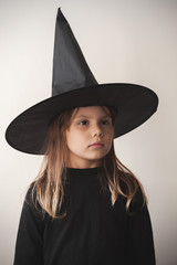 Girl in black witch costume over white wall