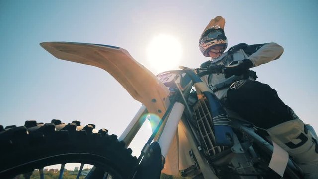 FMX rider is sitting on his motorbike against the sun