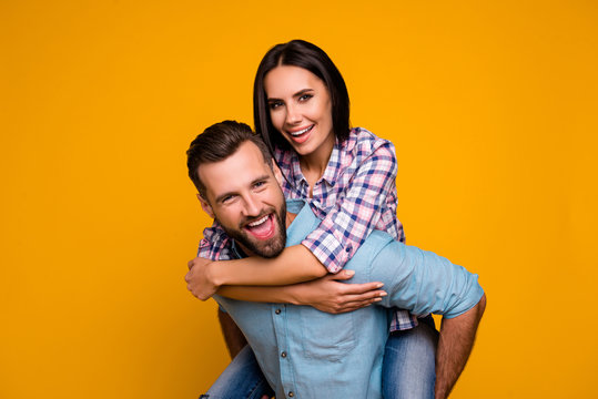 Ha-ha laugh laughter positive concept. Portrait of funky cheerful couple, handsome man carrying on back charming woman in piggy back style isolated on bright yellow background