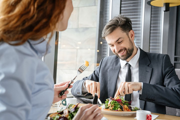 Businesspeople having business lunch at restaurant sitting man eating salad concentrated happy