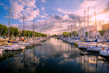 Fototapeta na wymiar Rimini cityscape. Yachts in water channel in Rimini at the sunset.