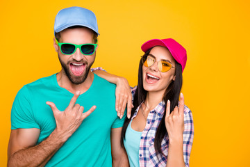 Portrait of funky crazy students in modern eyeglasses gesturing rock and roll symbols isolated on vivid yellow background. Clothes color bright creative concept