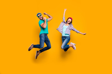 Fototapeta na wymiar Portrait of funky active couple jumping with raised fists celebrating victory wearing casual clothes isolated on vivid yellow background