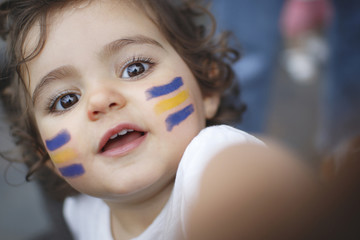 Kid fan with blue and yellow flag painted on face