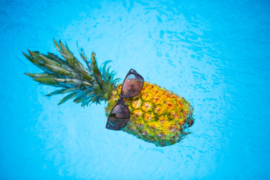 Pineapple with sunglasses in the pool, holiday feeling