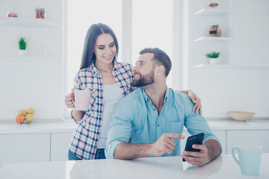 Portrait of handsome man showing sms with forefinger to charming woman using smart phone. Apps electronic wireless device technology social networks connection communication concept