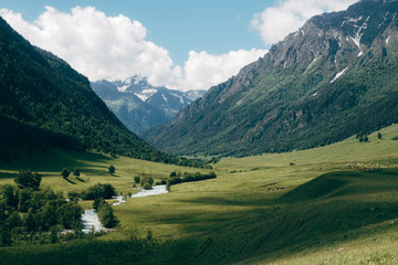 Obraz premium green mountain valley landscape with blue sky and white clouds. Deep shadows lies on a meadow