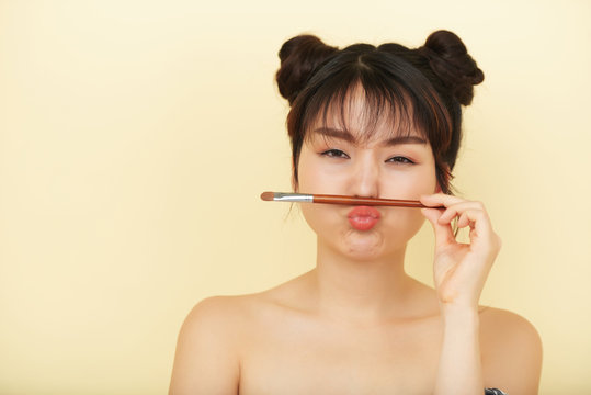 Portrait of cute Asian girl with brush isolated on beige background