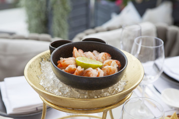 the Shrimps with lime in a cast-iron bowl in the ice on a table in a restaurant