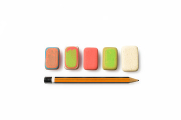Pencil and erasers on white background. Close up of a orange and black wooden pen and some multicolors erasers.