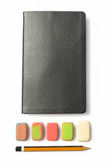 Pencil, eraser and notebook on white background. Close up of a wooden pen orange and black, an multicolor erasers and a booklet black. A diary with instruments for writing