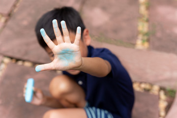 Little boy with dirty hand of blue chalk
