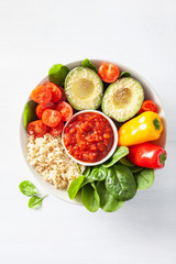 vegan buddha bowl. healthy lunch bowl with avocado, tomato, bell peppers, quinoa and salsa