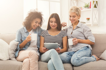 Three friends using tablet and drinking coffee