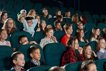 Group of stylish teenagers and children expressing facial emotions in movie theatre. Smiling...