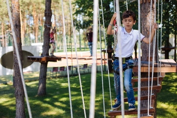 Fun pastime. Cheerful preteen boy enjoying himself at a rope park while walking down the trails