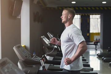 Fototapeta na wymiar Young sporty man on treadmill in fitness club