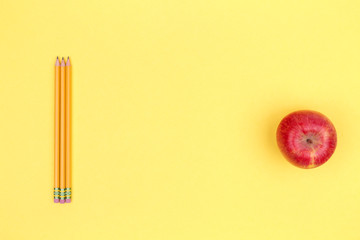 Pencils and apple on a yellow background. Back to school concept