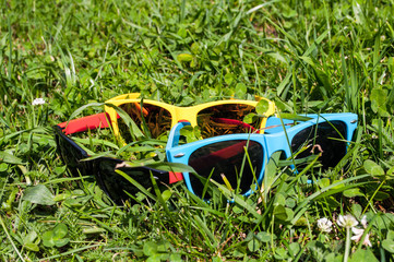 Blue red and yellow sunglasses in the green grass with mobile phone