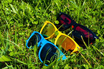 Blue red and yellow sunglasses in the green grass with mobile phone
