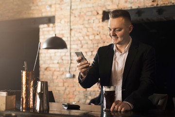 Young man sitting at bar counter and using smartphone