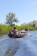 Fototapeta na wymiar Ffisherman manages a boat with oars on Danube River