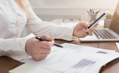 Secretary using smartphone and reading documents