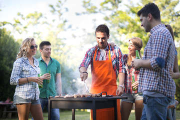 Happy students having barbecue on summer day