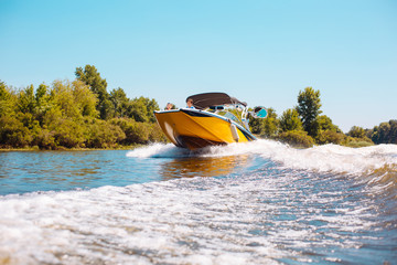 Best weekend. Happy young family sailing a motorboat down the river while two kids peeking from the...