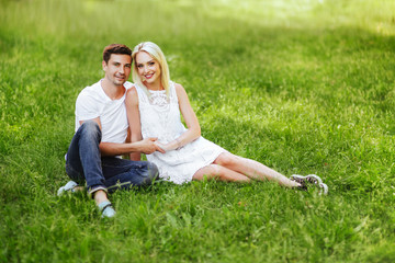 The lovely couple in love sitting on green grass.