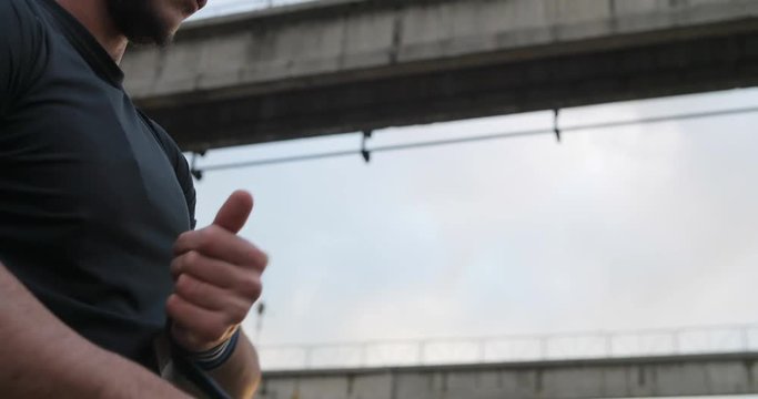 Close uo shot of muscle sports man with fist bandage and training weights preparing for morning workout outdoor. Urban, industrial. Strength and motivation.Fitness man warming up