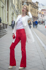 Fashionable young blonde in a spring fashionable suit and with a shopping bag in the center of Moscow

