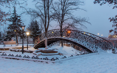 Circle bridge and statue in the winter season in Odessa. Snow evening time
