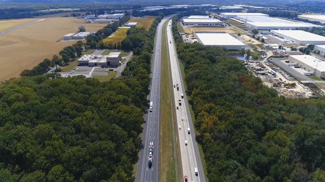 Aerial of Interstate 95 Highway with woods and warehouses, tilting upward to the horizon