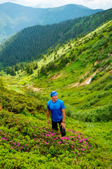 Fototapeta na wymiar Joyful adventurer climbs the green mountain slope