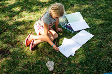 Girl sitting on grass doing homework