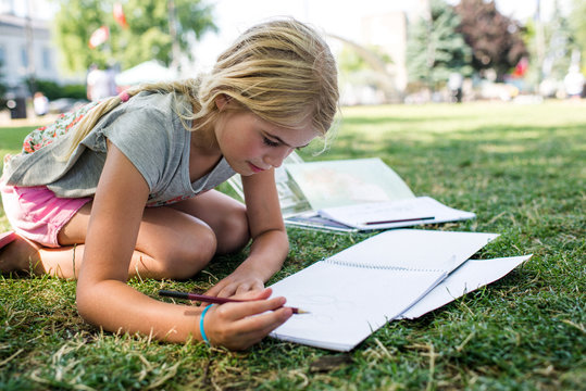 Girl sitting on grass doing homework