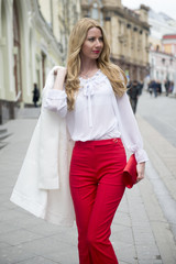 Fashionable young blonde in a spring fashionable suit and with a shopping bag in the center of Moscow
