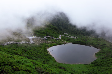 Xima Pond on the top of Mount Cangshan, with people walking along the path in the background. Legend has it that Kublai Khan led his army passing the mountain and washed his horse here.